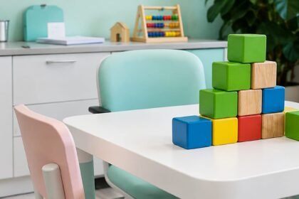 Sala de atendimento infantil com mesa, cadeiras e blocos coloridos, representando um ambiente de aprendizagem e intervenção comportamental.