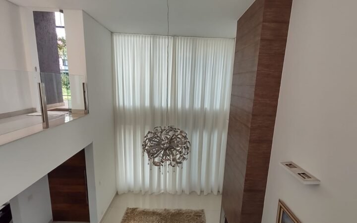 Cortina translúcida em sala com pé-direito duplo: a automação permite controlar a entrada de luz com um comando.